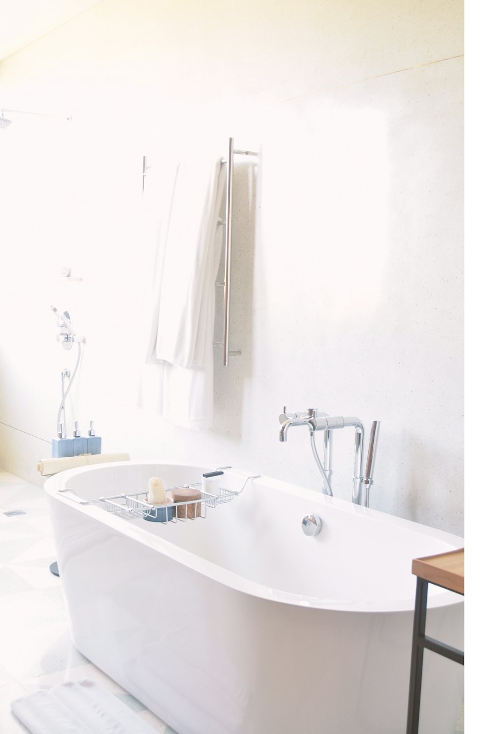 Freestanding bathtub with bath accessories on caddy.