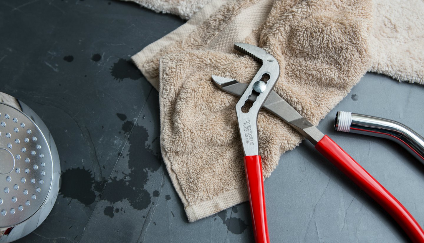Plumbing tools and parts laid out on a towel.