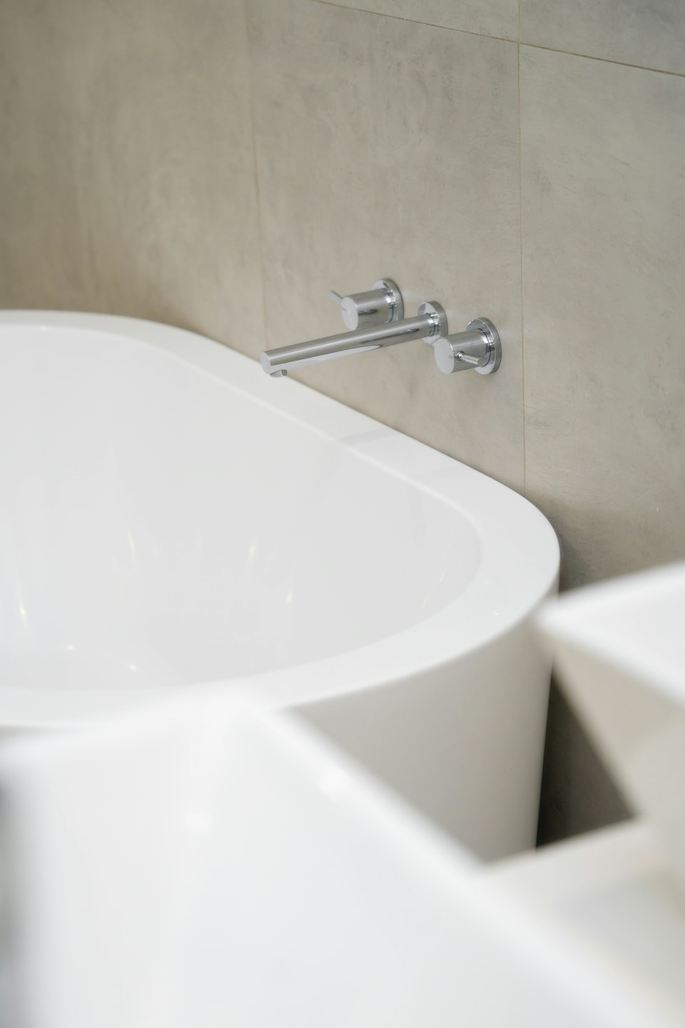 Modern white oval bathtub with a chrome wall-mounted faucet.